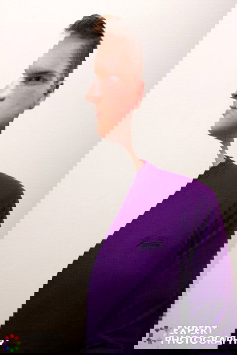 A man in purple jumper, with a creative cut out effect on his face which makes him look like a subject in a Picasso painting