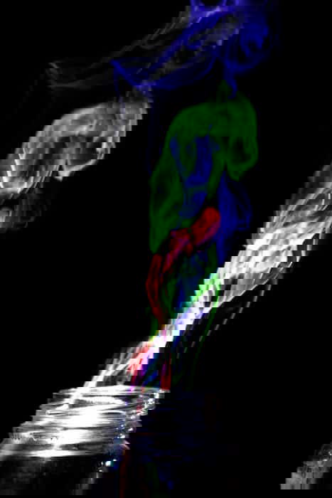 Multi Colored smoke coming from a glass jar, on black background. Achieved by the 'Harris effect' creative photography projects.