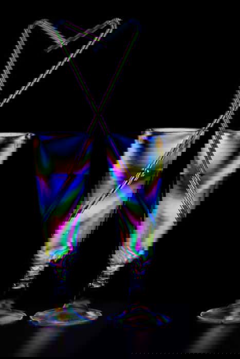 Two cocktail glasses filled with a multicolored photoelasticity effect on black background