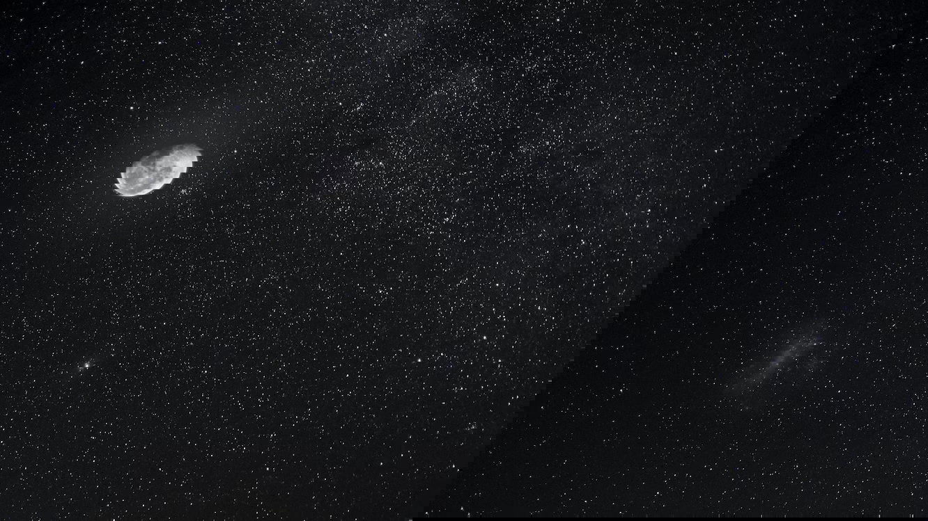 A bright half-moon in a night sky with stars