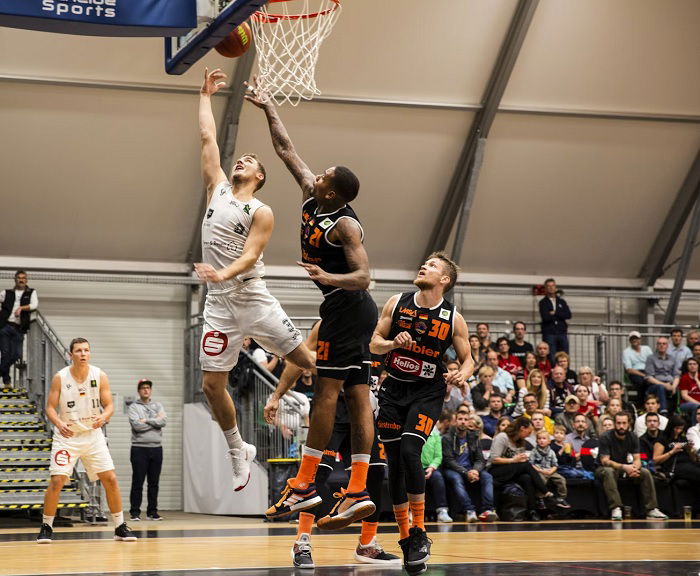 Two basketball players jumping by the hoop